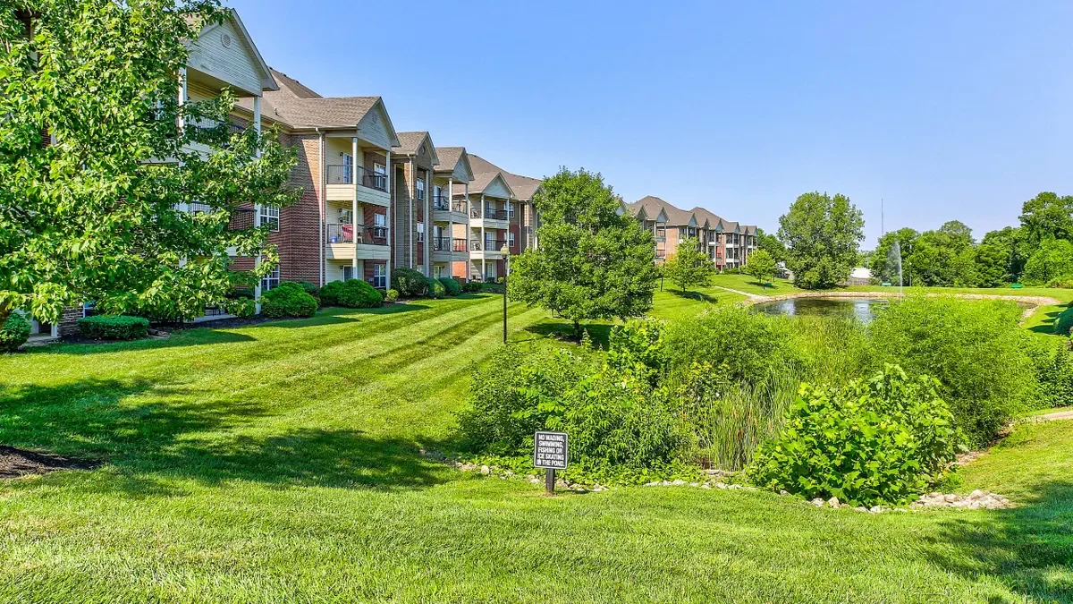 Garden apartments next to grass, trees and a pond.