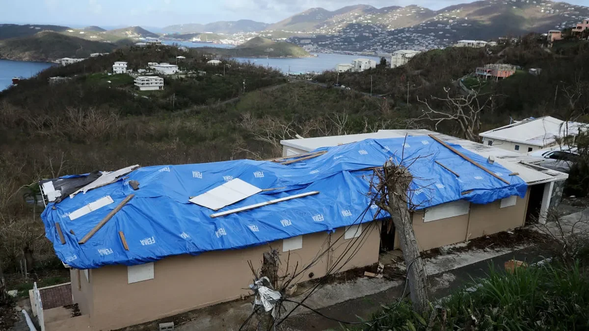 A blue tarp stamped with the FEMA logo covers the roof of a home damaged by Hurricane Irma.