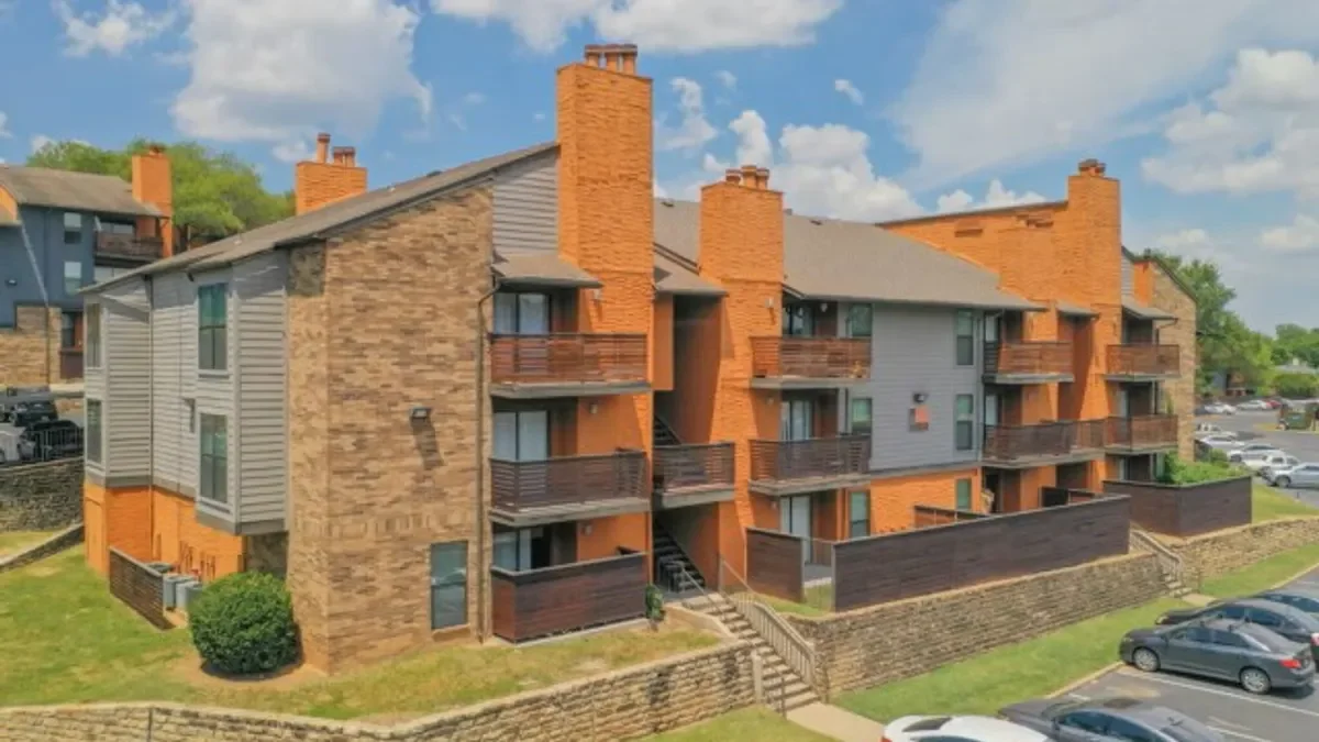 Brown brick and grey garden apartments with balconies.