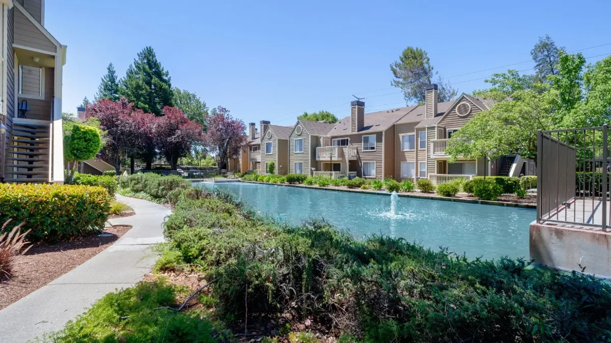 Tan, garden-style apartment property along a pond
